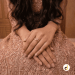 Gold-tone multi-band criss-cross ring with polished and textured intertwined bands, worn on a woman's finger.